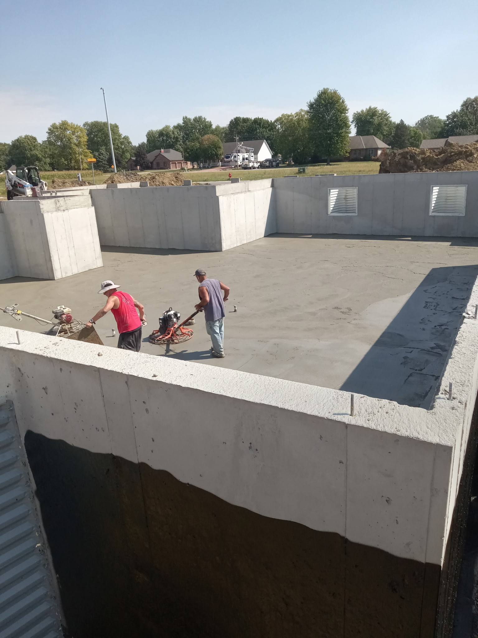 Crew finishing a basement foundation floor pour with a power trowel