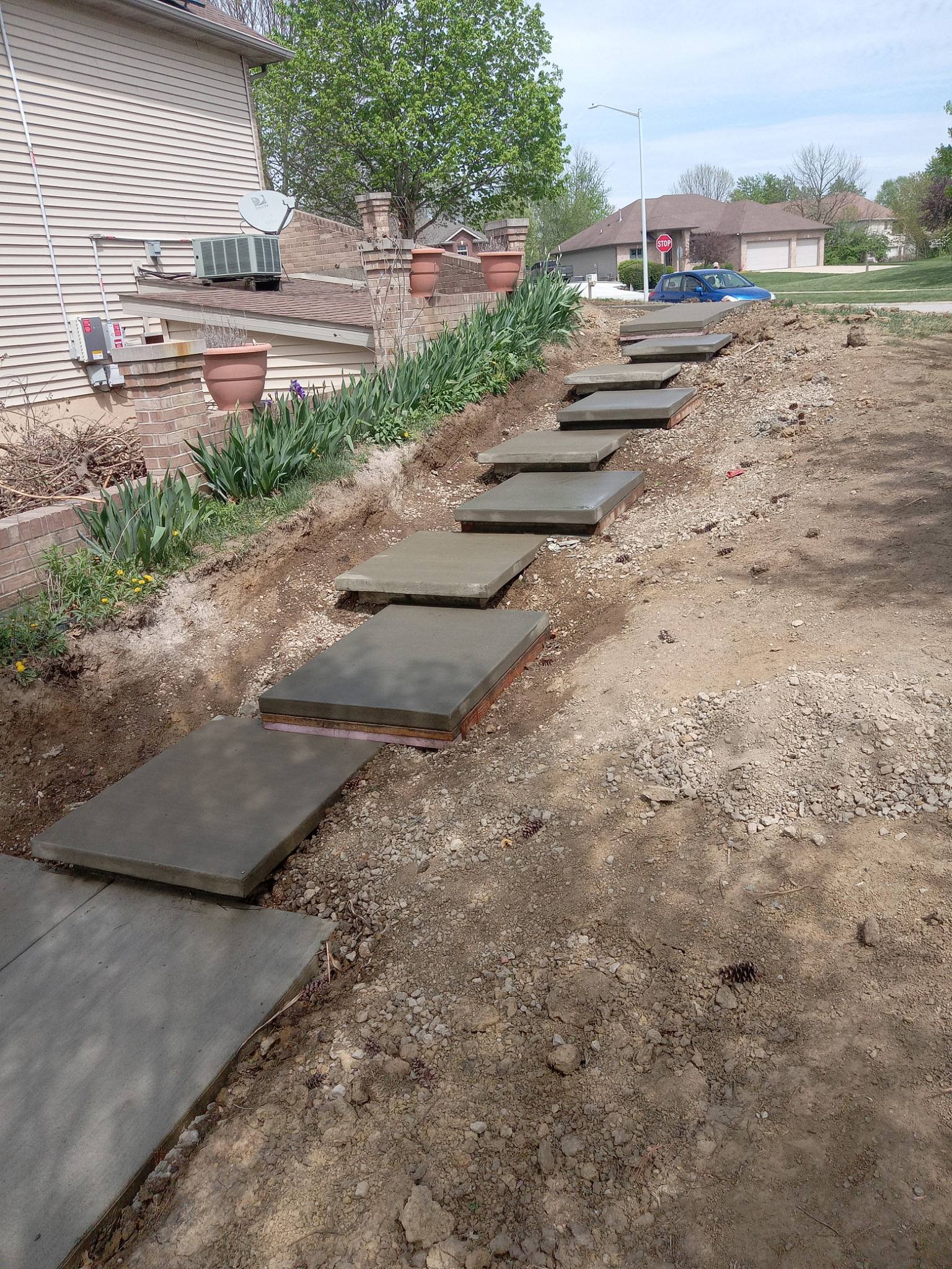 Custom concrete stepping-pad walkway on a sloped yard