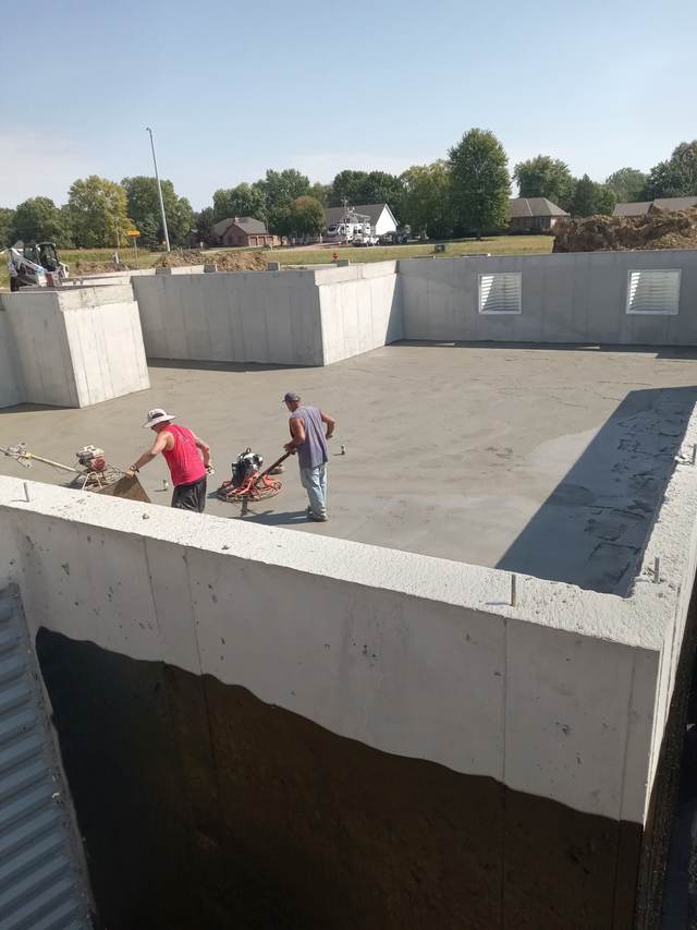 Crew finishing a basement floor pour with power trowel