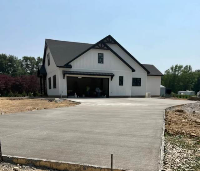 Concrete driveway leading to a new-construction farmhouse-style home